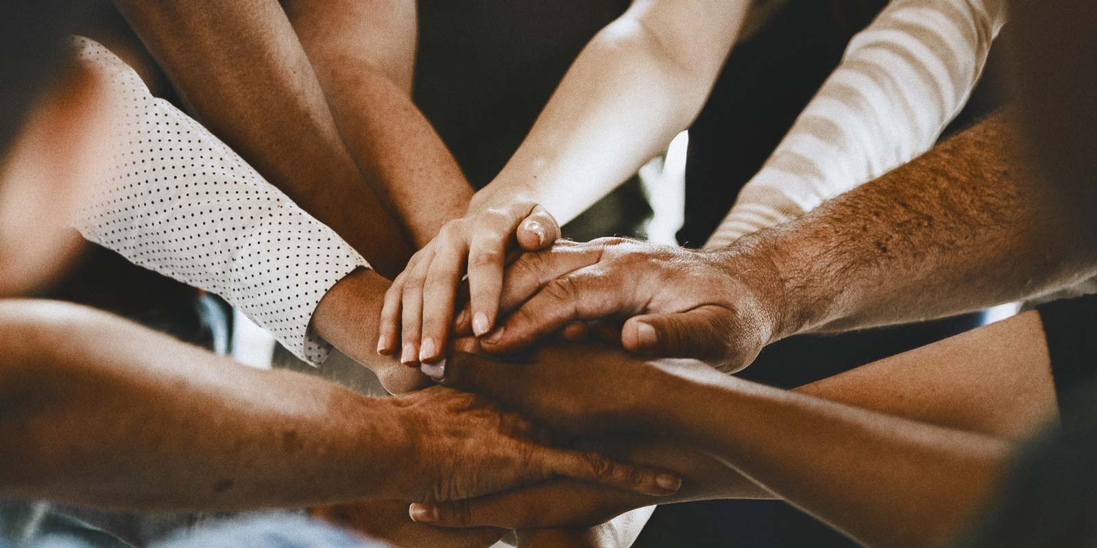 Stack of hands symbolizing teamwork and unity.